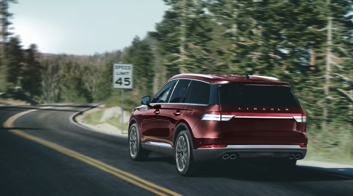 A 2024 Lincoln Aviator® SUV is being driven on a winding mountain road | Apple Lincoln Apple Valley in Apple Valley MN