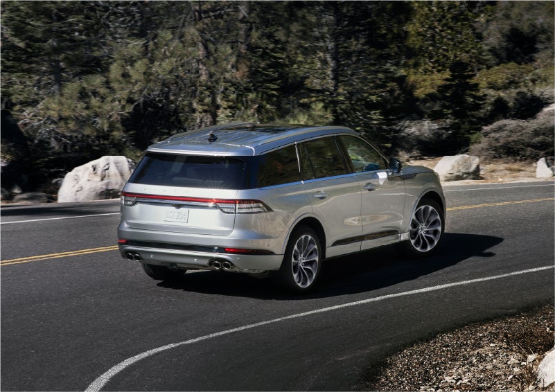A 2023 Lincoln Aviator® Grand Touring model is shown being driven on a tight turn of a mountain road | Apple Lincoln Apple Valley in Apple Valley MN