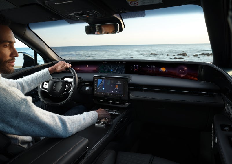 A driver of a parked 2024 Lincoln Nautilus® SUV takes a relaxing moment at a seaside overlook while inside his Nautilus. | Apple Lincoln Apple Valley in Apple Valley MN