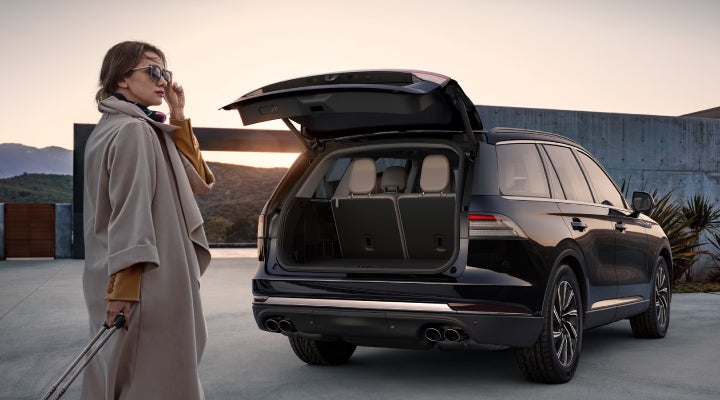 A woman approaches a 2026 Lincoln Aviator® SUV with its rear liftgate open. | Apple Lincoln Apple Valley in Apple Valley MN