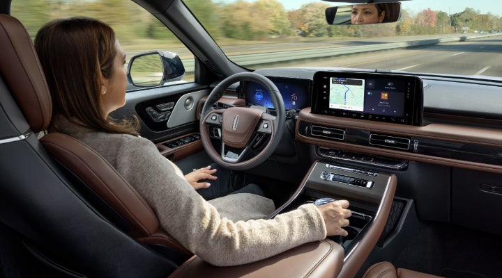 A 2026 Lincoln Aviator® SUV is being driven hands-free on a highway near a forest | Apple Lincoln Apple Valley in Apple Valley MN