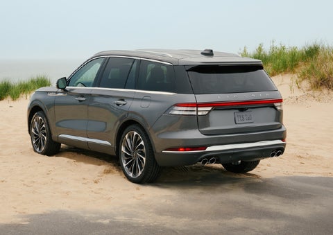 A 2027 Lincoln Aviator® SUV is parked next to sand dunes. | Apple Lincoln Apple Valley in Apple Valley MN