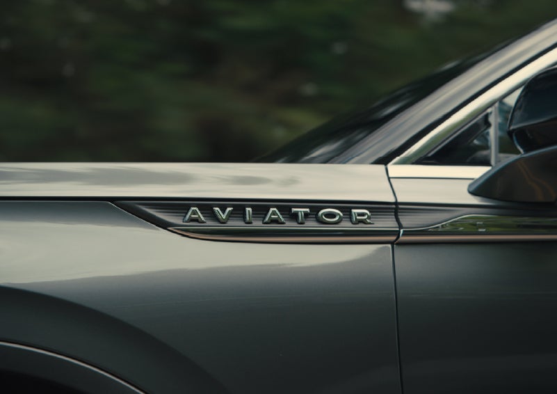 The driver’s side door and fender badging of a gray 2027 Lincoln Aviator® SUV are showcased. | Apple Lincoln Apple Valley in Apple Valley MN