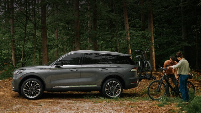 A father and son load e-bikes on a bike rack attached to a 2027 Lincoln Aviator® SUV. | Apple Lincoln Apple Valley in Apple Valley MN